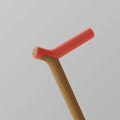 OOAK Uno walking stick with a coral-colored handle and oak shaft, showcasing natural wood grain and ergonomic design.