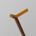 Ooak Uno walking stick with a walnut handle and kōwhai-colored shaft, showcasing a sleek, handcrafted design.