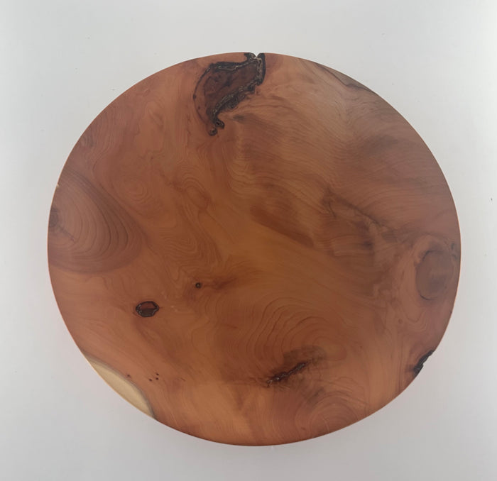 Round wooden plate with a natural grain pattern on a white background